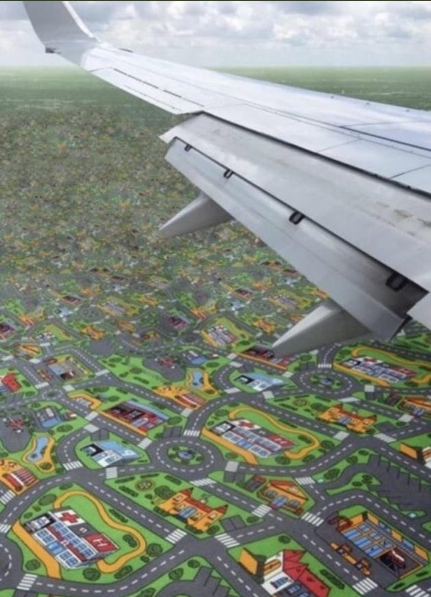 The image is a meme that uses a photo of a plane's window view of a city from a low altitude, but with the city's buildings and streets replaced with a children's playground toy called "Playmobil" city. The image is captioned "When you're so low that you can see the Playmobil". The idea is that the plane is so low that it's almost like a toy, and the city below is like a playset.